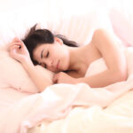 mujer durmiendo plácidamente gracias a una buena ubicación de la cama en el dormitorio según el Feng Shui.
