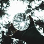 Una mano sosteniendo a contraluz en un bosque una bola de cristal. Genera un ambiente de sinergia entre la naturaleza y las energías invisibles. Símil entre lo que ocurre entre la Geobiología y el Feng Shui.