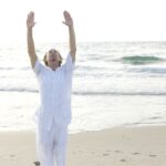 Un hombre joven practicando Qi Gong en la playa, arte de la metafísica china y de gran sabiduría oriental.