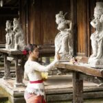 Mujer joven balinesa haciendo una ofrenda en un templo.