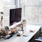 Escritorio en una habitación clara con luz natural. Todos los elementos (pantalla, libretas, lápices, etc.) bien dispuestos según el Feng Shui para ser productivo.