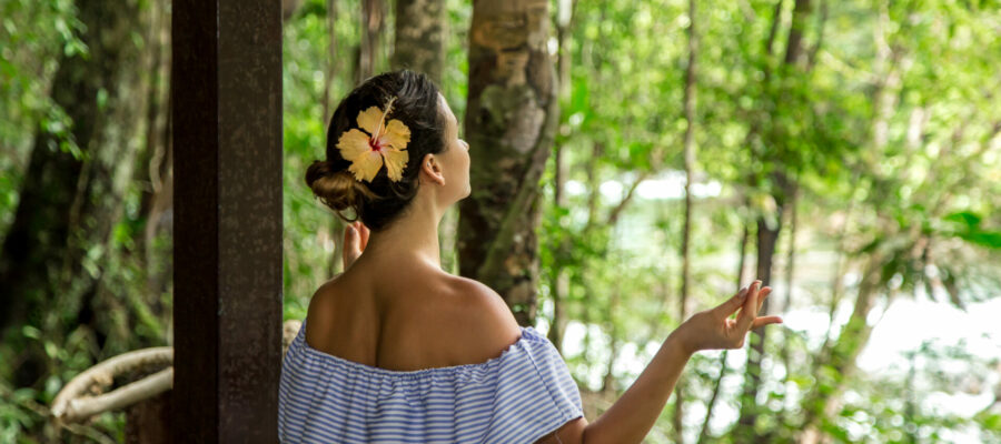 Mujer joven de espaldas meditando en silencio en Bali, en el bosque. Nyepi es el día de silencio en Bali.