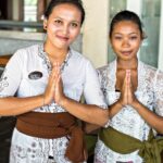 Dos jóvenes malasias vestidas con el vestido tradicional y con las manos juntas, símbolo de gratitud. Están dando las gracias.