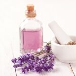 Un frasco lleno de aceite de lavanda casero. Planta de lavanda y mortero pequeño para su elaboración. Manera de crear aromas naturales sin generar tóxicos en casa.
