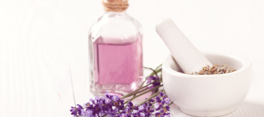 Un frasco lleno de aceite de lavanda casero. Planta de lavanda y mortero pequeño para su elaboración. Manera de crear aromas naturales sin generar tóxicos en casa.