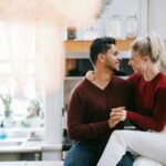 Una pareja joven y atractiva en su casa. Están abrazados y sonrientes. Felices de haber aplicado el Feng Shui en su hogar.