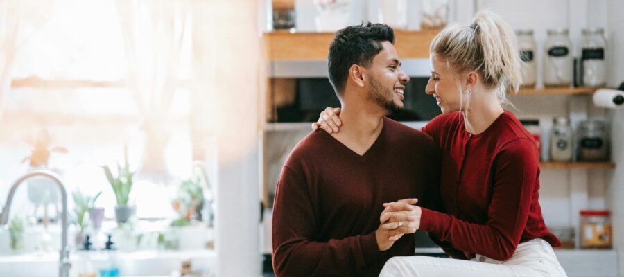 Una pareja joven y atractiva en su casa. Están abrazados y sonrientes. Felices de haber aplicado el Feng Shui en su hogar.