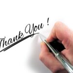 Una mano con un bolígrafo escribiendo 'Thank You' (Gracias), para mostrar gratitud.
