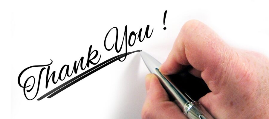 Una mano con un bolígrafo escribiendo 'Thank You' (Gracias), para mostrar gratitud.