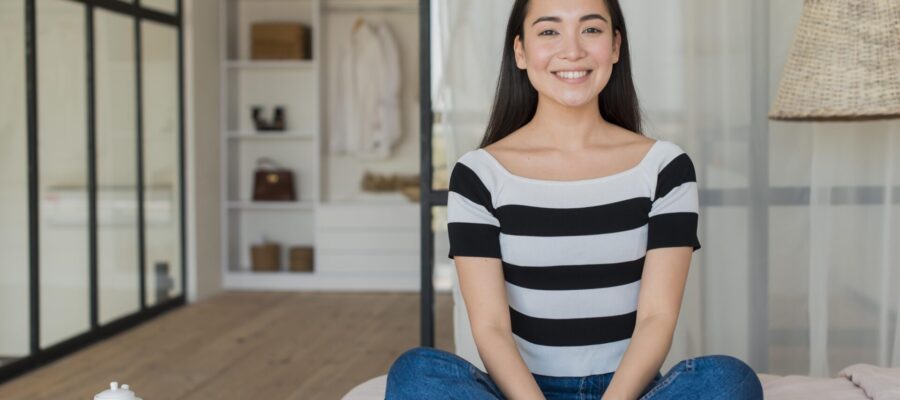 Mujer oriental, feliz, sentada en una zona de su casa que está preparada para la meditación.